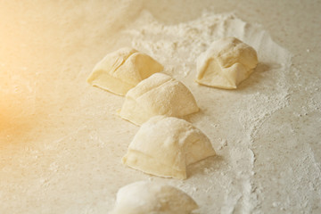 chopped raw kneaded dough into pieces on the table against the background of the kitchen interior. cooking baking dish