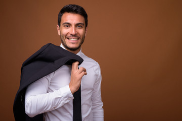 Young handsome Hispanic businessman against brown background