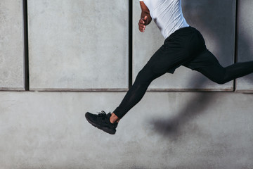 Athlete running against concrete wall.