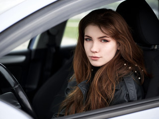 Fototapeta na wymiar Close up portrait of young attractive red hair self-employed business woman driver sitting in white car stuck in a city traffic jam staring into camera running late to work noonday bleached colors