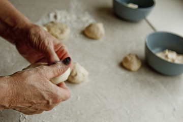 women's hands cut the raw kneaded dough into pieces on the background of the kitchen interior. cooking baking dish