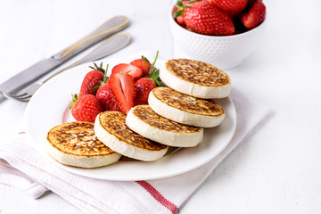 Homemade Cottage Cheese Pancakes with Ripe Strawberry on White Plate on White Wooden Background Tasty Healthy Breakfast or Lunch Horizontal