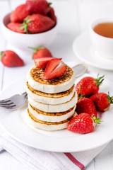 Stack of Homemade Cottage Cheese Pancakes with Ripe Strawberry on White Plate on White Wooden Background Tasty Healthy Breakfast or Lunch Vertical