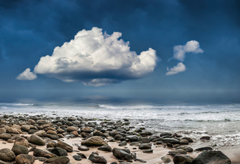 Fototapeta na wymiar Great cloud approaching cobbled beach