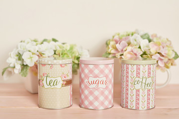 cans for loose on a wooden light background near flowers
