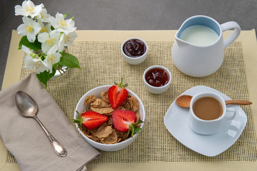 Light Breakfast coffee with milk and muesli, fresh strawberries, jam. Decoration of white delicate flowers.