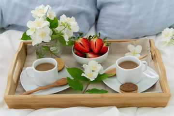 Breakfast in bed for two. Wooden tray with coffee, strawberries and cookies. Jewelry with delicate...