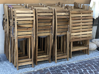 Wooden chairs folded near the wall close-up. Cafe interior. Wooden outdoor furniture