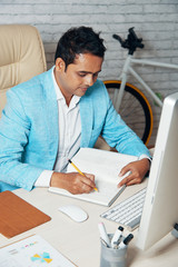 Fototapeta na wymiar Serious businessman preparing for business presentation he making some plan in notepad while sitting at workplace at office