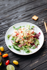 Fresh salad with chicken, cheese, leaves, beets, spinach on a dark wooden background