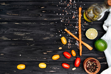 Dark wooden kitchen table with spices, tomatoes, lime and olive oil on top. Flat lay in the kitchen