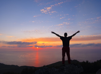 man doing sports with raised arms in front of blue sky and sunset over the sea, Euskadi