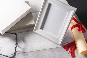 white blank photo frame and education or graduation equipment on wooden white table