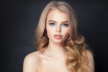 Fototapeta premium Cute woman with blonde curly hair on dark background