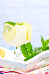 Summer cold refreshing drink with fruit, lbdo and mint. Lemonade with fruit on a white tray with a bright napkin.. Copy space.
