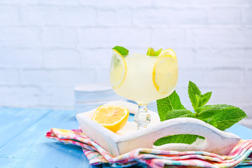 Summer cold refreshing drink with fruit, lbdo and mint. Lemonade with fruit on a white tray with a bright napkin.. Copy space.