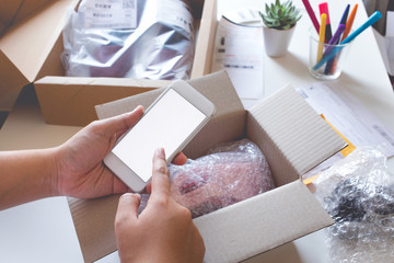 Online shopping concepts with young female buying product  on smartphone and some her product on table.