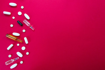  Tablets, ampoules and capsules. Medical preparations on a red background. Flat layout, copy space