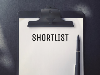 Business or Job Hiring concept - Top view of a clipboard and white sheet with SHORTLIST written on...