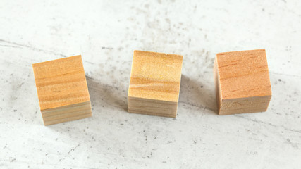 Three blank wooden playing cubes on white board