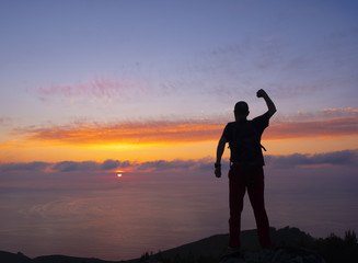 Fototapeta premium Man on the mountain at sunset, celebrating success when reaching the top, Euskadi, Spain