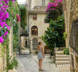 Young woman stops to observe the beautiful architecture of Saint Paul de Vence.