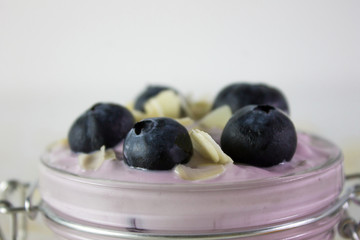 In this photo we can see a handmade blueberry yogurt decorated with blueberries and almonds in a close plane.