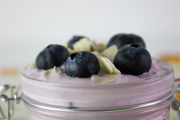In this photo we can see a handmade blueberry yogurt decorated with blueberries and almonds in a close plane.