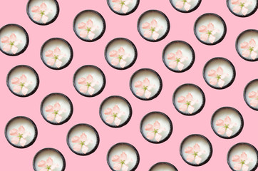 On a bed of coral background are many open jars of cream, in a jar is a flower.