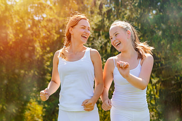 Fototapeta premium Two young female friends jogging trough the forest.Spring exercise and workout.Lifestyle