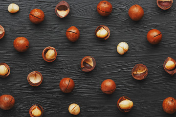 Purified and shell repeats macadamia nuts on black textural stone background. Healthy eating...
