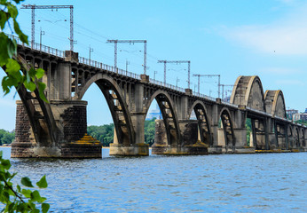 Beautiful landscape of the Ukrainian  Dnipro city with old arch railway Merefo-Kherson bridge across the Dnieper river in Dnepropetrovsk, Ukraine. Bridge in spring and summer
