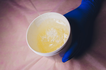 wax for sugaring in a cosmetic jar in the hands of a master in a beauty salon.