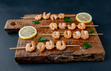 Grilled shrimp shashlik. shrimps with parsley and lemon on the background of concrete