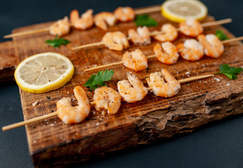 Grilled shrimp shashlik. shrimps with parsley and lemon on the background of concrete