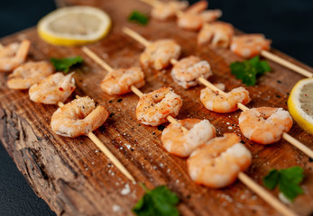 Grilled shrimp shashlik. shrimps with parsley and lemon on the background of concrete