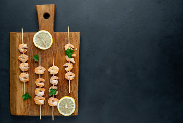 Grilled shrimp shashlik. shrimps with parsley and lemon on the background of concrete, with copy space for your text