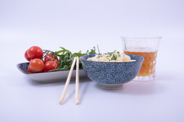 Noodles In A bowl with Fresh salad, a beer and chopsticks. White background