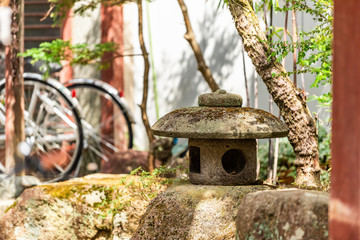 Takayama Japan with small garden and stone lantern with bicycles in background during day