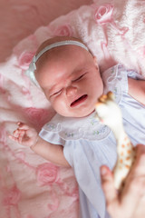 Fototapeta na wymiar 2 month old baby girl in pretty dress crying