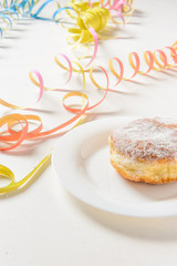 Krapfen auf weißem Teller vor weißem Hintergrund mit bunten Luftschlangen