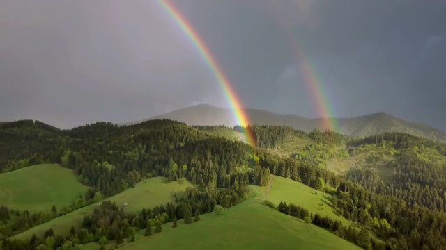 Aerial view of beautiful double rainbow over green forest country
