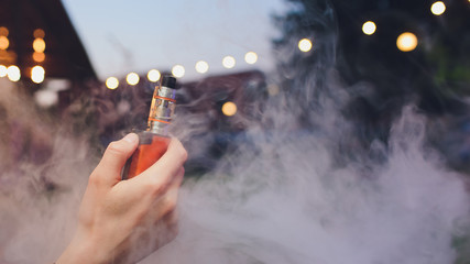 Man is smoking electronic cigarette or vaporizer.