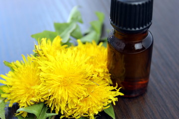 A bottle of oil on a background of yellow dandelion