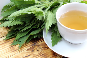 Cup of tea against the background of green juicy nettle