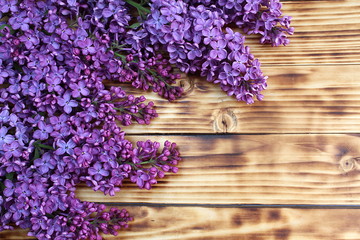 On a wooden table are several branches of lilac