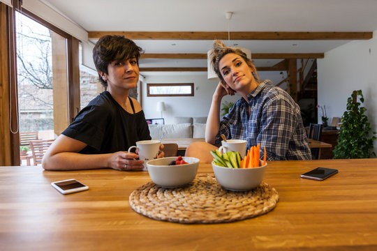 Two beautiful and young women having breakfast at home and having fun