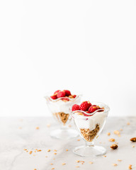 Fresh Raspberries on Top of Granola and Yogurt Parfait On Light Background, Space For Text