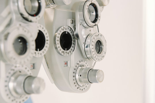 Modern vision test equipment and chair against white wall in optician office in clinic