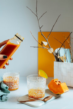 woman serving fresh mango smoothie into a glass